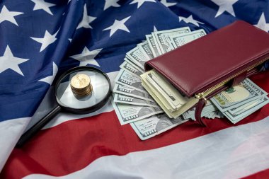 Büyük miktarda Amerikan doları büyüteç ve ABD bayrağında bir cüzdan ile yayılmış. Para hesap makinesi ve belgelerle izole edilmiş iş kavramı.