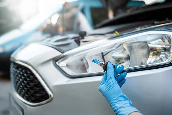 Stock image Close-up photo of a man's hands holding a car light bulb near the car for replacement. car repair lamp replacement or exchange. car headlight