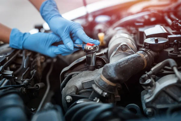 Close-up of the hands of a car mechanic who checks the oil in the car engine. Car or vehicle engine inspection and maintenance technician.