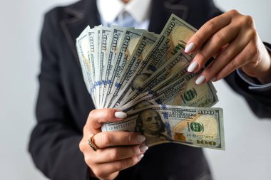 Kadın eli ceketinde banknotlar yığını görünüyor ve arka planda izole bir şekilde kutlanıyor. Eldeki para. İş kadını. Bayan patron.