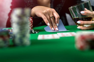 Elinde poker kartları ve fişleri olan seksi bir kadın masada poker oynuyor. Poker, yakalı bir elbise giymiş kumarbaz bir kadın.