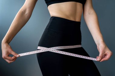 Yakın plan, eğitimli bir mideyi mezurayla ölçüyor. Spor, spor ve diyet konsepti. Vücut boyutlarının ölçümü