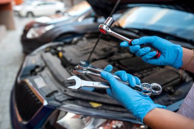 Tamirci, İngiliz anahtarı ve araba servisi ile araba tamirhanesinin motor tamirini yapıyor. onarım hizmetleri.