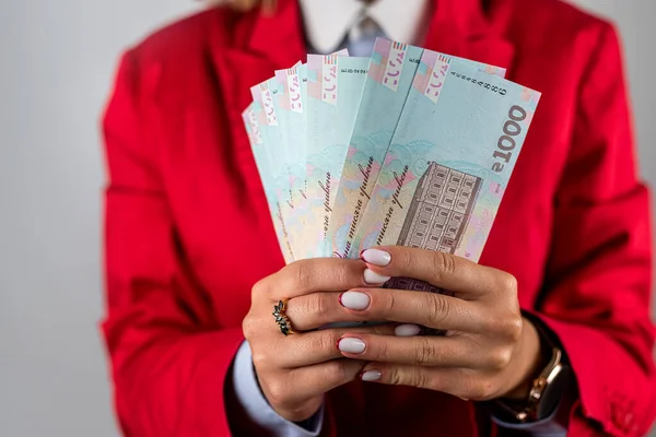 Beautiful young woman in a red jacket showing a pile of money in dollars isolated on a plain background. money. dollars in hand