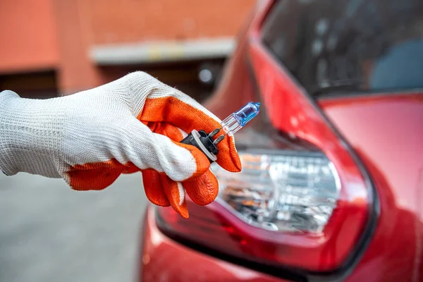 car lamp in a hand on the background of a car headlight. Car repair. a car mechanic changes a light bulb.
