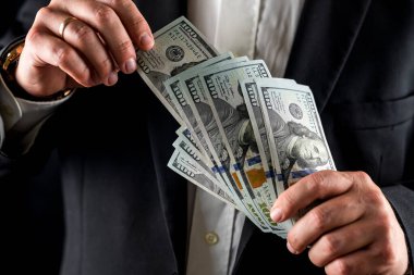 Bir iş adamı ya da banka çalışanının yüz dolarlık banknotları elleriyle sayması. İş konsepti. Finans bankacılığı. takas
