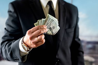 İş adamı bir aylık kazancını kendi ellerinde tutar. Para ve ticaret kavramı. Dolarla ellerini kapat.