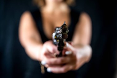 Siyah arka planda izole edilmiş tabancayla yüzsüz poz veren ciddi bir kadın. Silahla ateş etmek. Öldürücü silahı olan bir kadın.