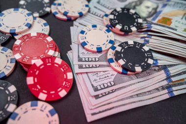 Arka planda izole edilmiş bir tomar doların arkasında çiplerle dağılmış iskambil kağıtları. Kumar oynuyorum. poker