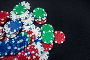 Siyah bir masaya saçılmış renkli kumarhane poker fişleri. yalnız poker. Kumarhane Kumar ya da para için oyun