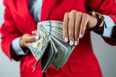 Beyaz arka planda izole bir şekilde duran kırmızı elbiseli genç bir kadının portresi. Para banknotlarını gösteriyor. Kadın patron işi. Para için. para