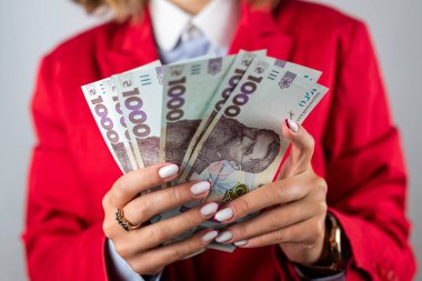 Çok sayıda dolar, yakın çekim ve güzel genç bir kadının ellerinde hryvnialar. İş ve zenginlik kavramı. Eldeki para