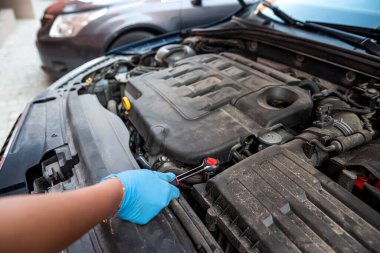 Araba tamircisi kaputu açık bir arabanın yanında bir araba motoru tamir ediyor. Araba bakımı. onarım hizmetleri.