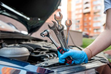 Araba tamircisi kaputu açık bir arabanın yanında bir araba motoru tamir ediyor. Araba bakımı. onarım hizmetleri.