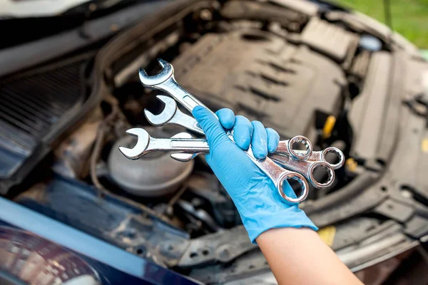 car mechanic repairs a car engine in a car workshop with a wrench. car maintenance. repair services.