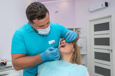 the chief dentist examines the treated healed teeth in a young woman. The concept of preventive examination in dentistry