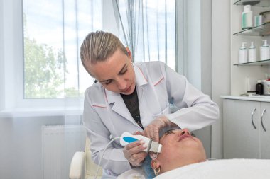 Bir güzellik salonunda yüz derisinin ve vücudun darsonvalleşmesini gerçekleştiren profesyonel bir kozmetikçi. Kozmetoloji konsepti. Güzellik prosedürleri