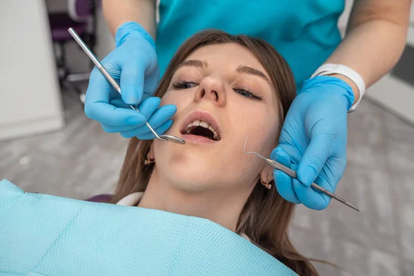 professional woman dentist performs a professional examination of the oral cavity in a beautiful woman. Health concept