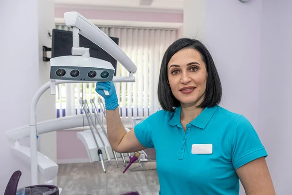 young female dentist in a private clinic with modern dental equipment standing and smiling. Healthcare concept