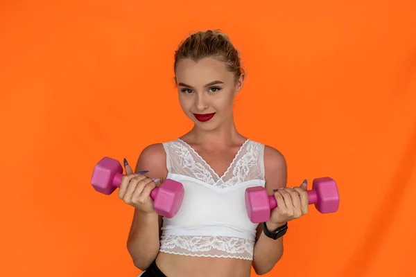Sporty young woman working out with dumbbells isolated on plain background. Sporty woman concept