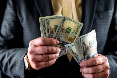 Bir iş adamı ya da banka çalışanının yüz dolarlık banknotları elleriyle sayması. İş konsepti. Finans bankacılığı. takas