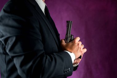 Bir polis memuru önünde silah tutuyor. Sade bir arka planda izole edilmiş kırpılmış bir polisin portresi. tabanca ellerinde.