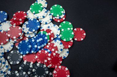 Siyah bir masaya saçılmış klasik renkli yuvarlak poker fişleri. İzole poker konsepti. Kumar.