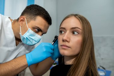 KBB doktoru, hastanede yapılan tıbbi muayene sırasında hastanın kulağını incelemek için bir otoskop kullanır. Kadın bir otolarolog ofisinde danışmanlık yapıyor..