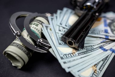 Silah ve mermiler etrafa saçılmış ve siyah cam masada Amerikan dolarları var. Kanun ve sorumluluk ihlali. ceza davaları