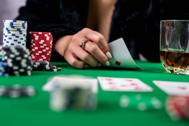 Güzel genç bir kız elinde kartlarla poker masasında oturuyor. Şans pokeri. Kadınların elinde poker kartları var.