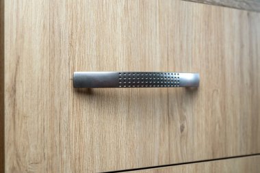 Doğal ahşap gardırop çekmecesine yakın plan, ön kapı kolu, arka plan.