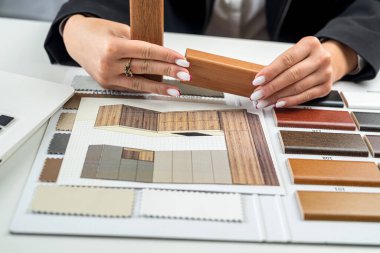 Tasarımcının eli, ev dekorasyonu projesi için ev içi tasarım örneklerinden döşeme ve mobilya malzemeleri seçer. Tahta örnekleri.