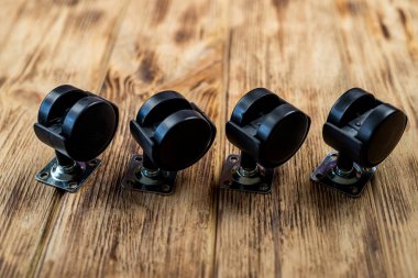 Ağaç zemininde siyah lastik tekerleklerin üst görüntüsü. Mobilya çarkı mobilya montajı ve parçaları onun için