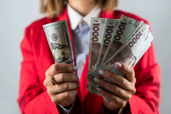 Çok sayıda dolar, yakın çekim ve güzel genç bir kadının ellerinde hryvnialar. İş ve zenginlik kavramı. Eldeki para