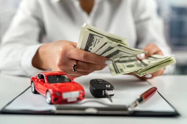 一个女商人带着一辆小车在桌子上忙着办理保险文件 汽车和人寿保险 桌上的美元 — 图库照片