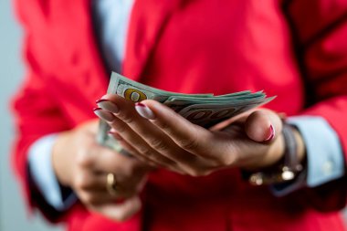 Beyaz arka planda izole bir şekilde duran kırmızı elbiseli genç bir kadının portresi. Para banknotlarını gösteriyor. Kadın patron işi. Para için. para