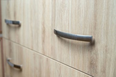 Doğal ahşap gardırop çekmecesine yakın plan, ön kapı kolu, arka plan.