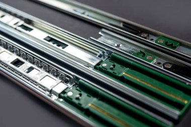 Mobilya yapılarındaki çekmeceleri taşımak için metal raylar. Marangozluk atölyesinde ev eşyaları montajı için aksesuarlar. Siyah arkaplanda izole.