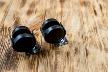 Bir ofis sandalyesi için mobilya çarkı ya da tekerlek masanın arka planına yerleştirilir. Yakın çekim görüntüsü. Mobilyalar için siyah tekerlekler