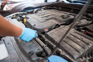 Araba tamircisi bir araba atölyesinde ingiliz anahtarıyla araba motoru tamir ediyor. Araba bakımı. onarım hizmetleri.