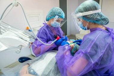 İşinin ehli bir dişçi ve asistanı diş implantı takmak için ameliyatı ofiste yaparlar. Diş hekimi kavramı