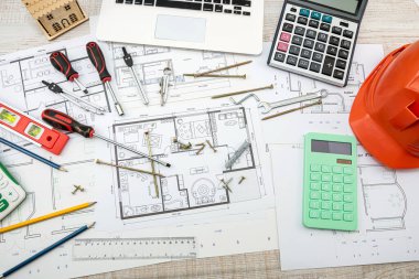 Taslak çizimler ve inşaat araçları inşaat arka planına saçılmış durumda. çizim araçları