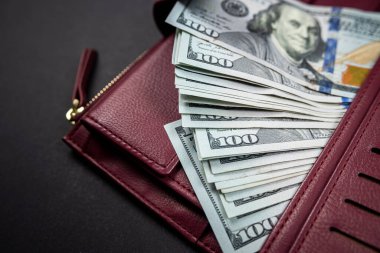 Tahta bir masanın üzerinde para dolu deri cüzdan ve üzerinde Başkan Franklin 'in portresi olan yüz tane Amerikan banknotu. 100 dolarlık nakit para. kağıt para birimi arkaplanı.