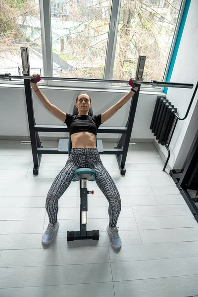 Beautiful female trainer is training on the exercise machine in the fitness gym to be in good shape. the concept of a female trainer who devotes a lot of time to training