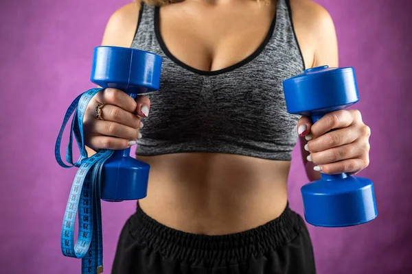 Young fun strong sport sports fitness trainer instructor woman in tracksuit holding dumbbells isolated on plain background. Sport workout concept