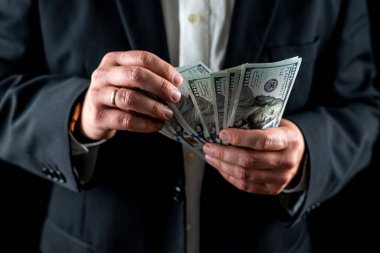 şık takım elbiseli adam birikimlerini dolar banknotlarıyla sayıyor. Eller dolar sayıyor. Takım elbiseli bir adam.
