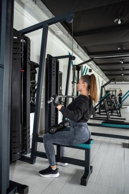 Güzel genç müşteri sırt kasları için simülatör üzerinde egzersiz yapıyor. Duruş konsepti. Sırtım sağlıklıydı..