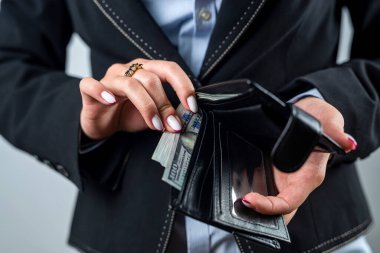 Çantasına bir dolarlık banknot koyan kadın ellerine yakın plan. Cüzdana dikkat et. Para için. Cüzdanında dolar var. zengin kadın