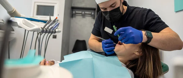 Pretty lady in the dentist's chair looking at her doctor close-up while the dentist is examining her teeth. the concept of examination of a patient with problems in the oral cavity