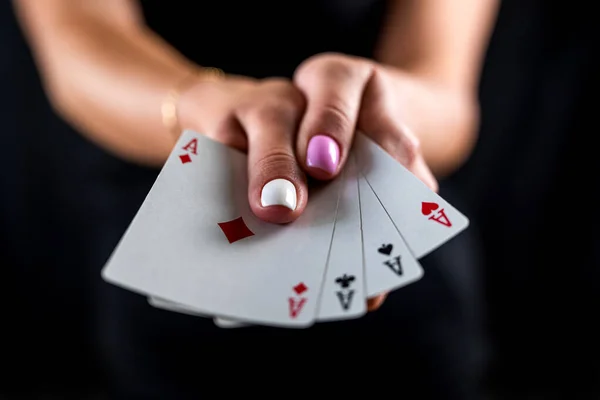 Photo of a young pretty glamorous charming woman holding a card in her hands isolated on a black background. poker game of chance